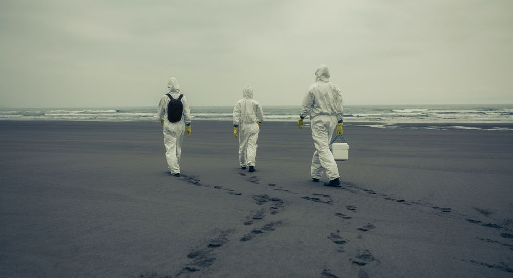 People with bacteriological protection suits walking on the beach