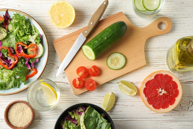 Ingredients for salad, kitchen supplies and oil on wooden background, top view