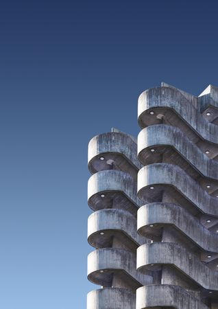 Curves of a brutalist car park against a blue sky