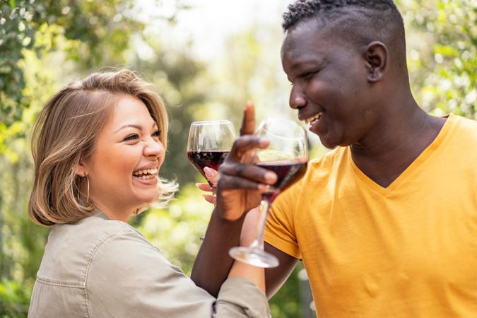An interracial couple shares a toast with glasses of red wine