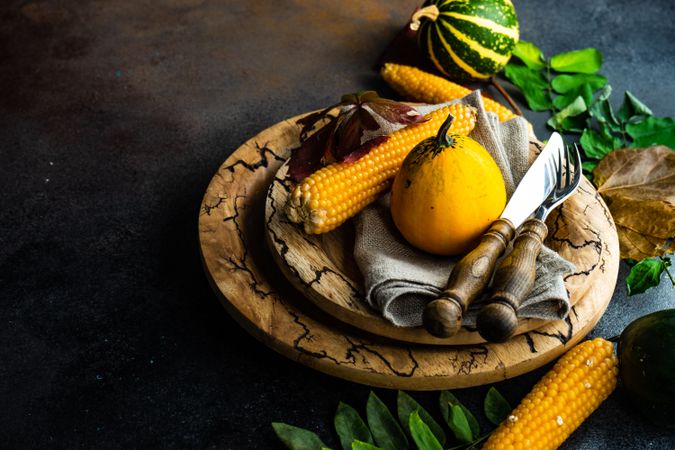 Rustic autumnal table setting with mini squash, corn and leaves