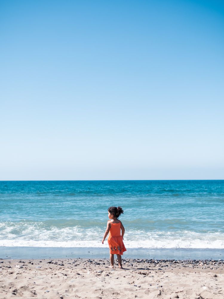 Little girl standing on beach and admiring view
