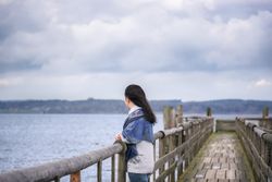 Woman on a bridge over alpine lake looking in the distance