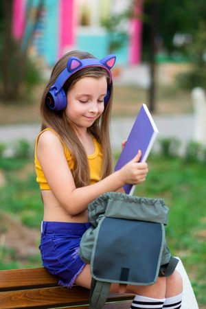 Preteen school girl with book on bench in park