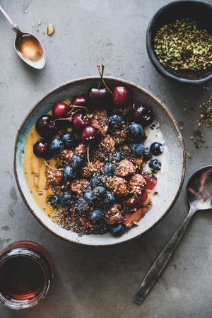Oat granola yogurt bowl with cherries, blueberries, honey, nuts