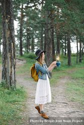 Woman with hat and holding burning gas lamp in the woods 5XWnr0
