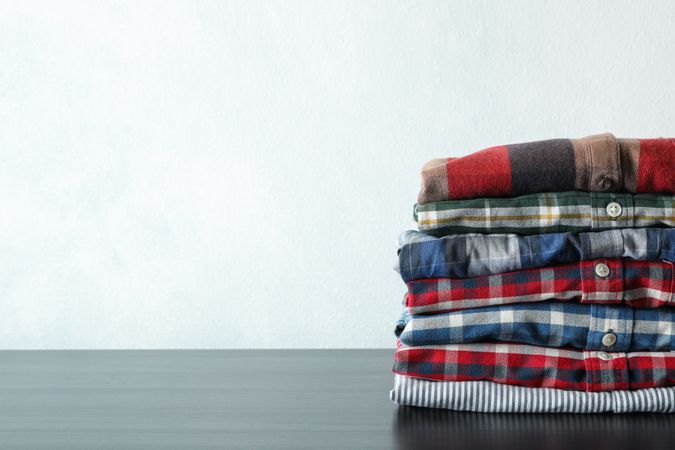 Stack of different shirts on table, space for text