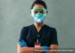 Portrait of Black female doctor with arms crossed in PPE gear 0VYGOb
