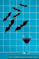 Bats flying above a cocktail glass on blue background 48Y2Rb