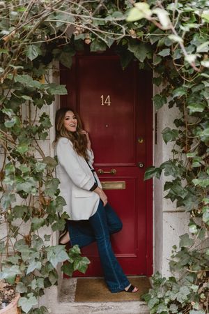 Stylish woman standing near red door