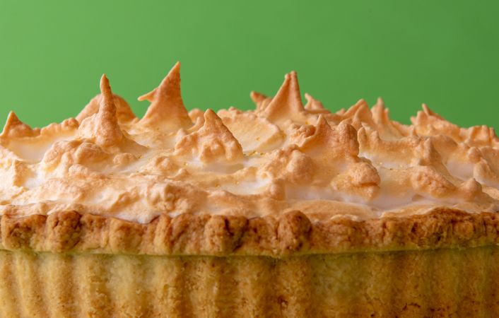 Lemon meringue pie, extreme close-up, isolated on a green background