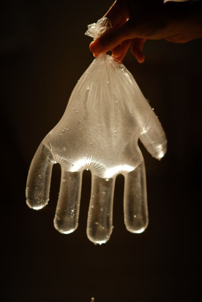 Crop person with disposable glove full of water