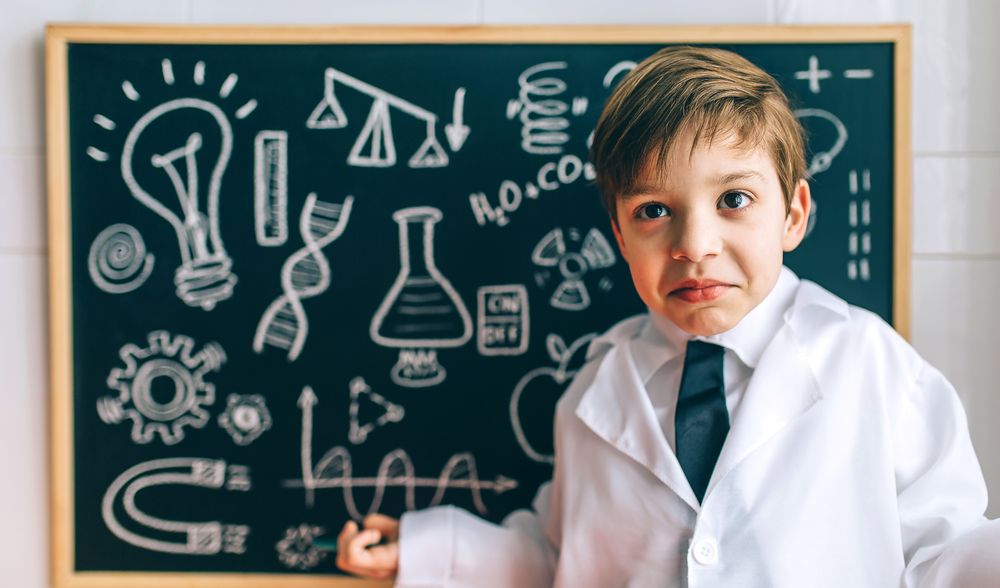 Child dressed as a scientist in front of chalkboard