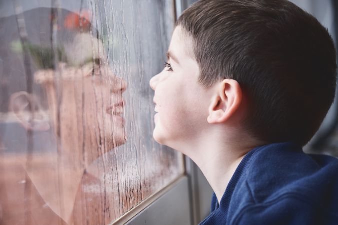 Boy breathing on wet glass