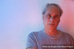 Portrait of sad middle aged man in gray shirt against light wall 0vK9R5