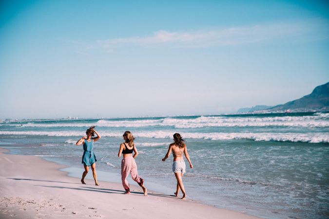 Group of young women walking on the sand at the beach