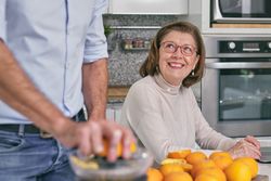 Crop man making fresh juice near smiling senior mom