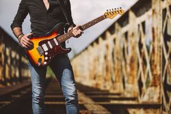 anonymous Man with guitar standing on bridge