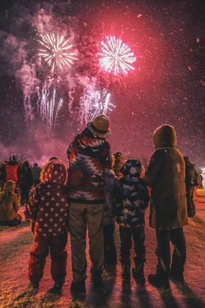 Family watching colorful firework display during nighttime