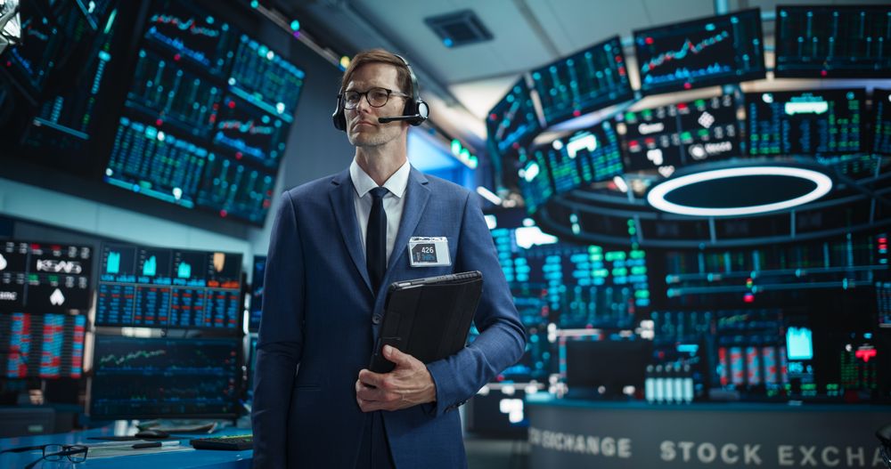 Productive Stock Exchange Broker Wearing Glasses, Holding a Tablet Computer.