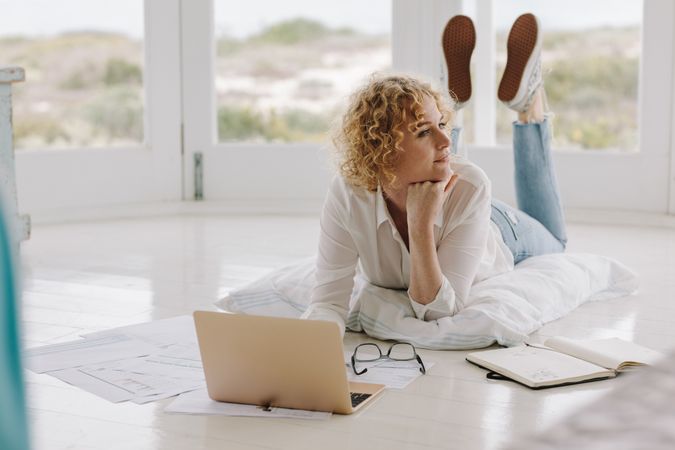 Woman working from home lying on floor