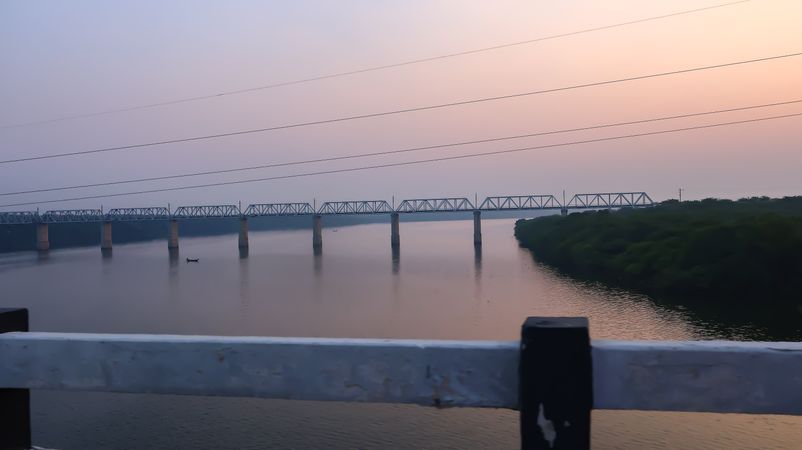 Railway Bridge Over River During Sunset With Lush Green Banks