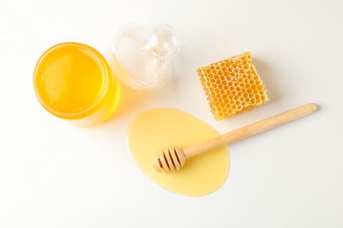 Jar with honey, dipper and honeycomb on neutral background, copy space