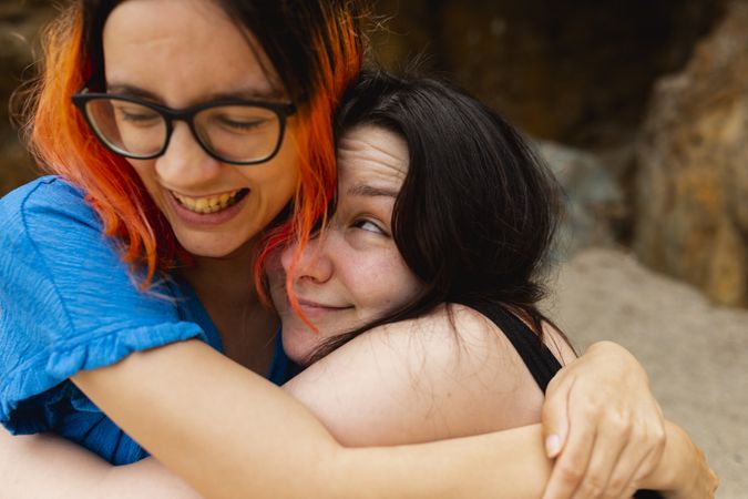 A couple of young women hug each other with affection and joy during a day at the beach