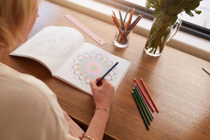 Woman coloring designs with color pencils for relaxation at home
