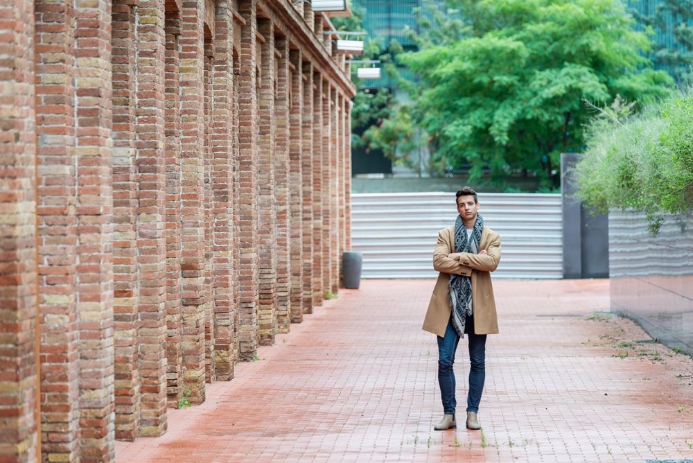 Portrait of young man with arms crossed standing on brick road