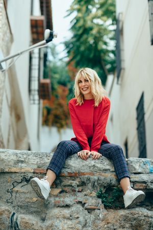 Content blond woman sitting on stone wall