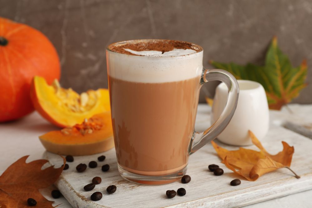 Composition with glass cup of pumpkin latte on light background
