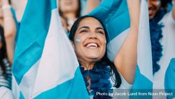 Woman with garland and Argentina flags cheering from stadium fan zone 0WnkOb