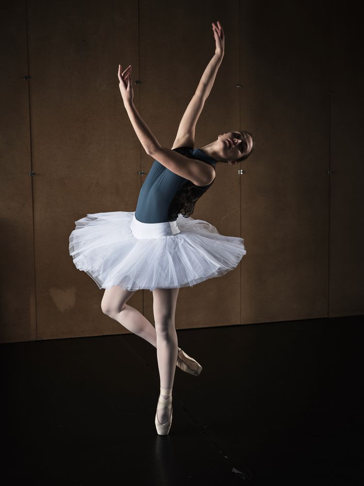 Graceful ballerina in tutu rehearsing ballet role in studio