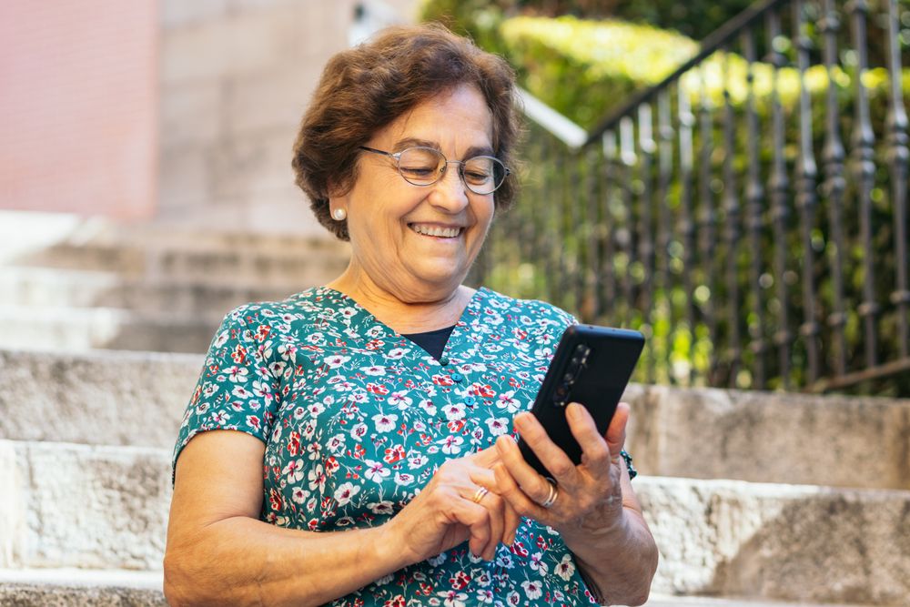 Smiling older woman using smartphone outdoors