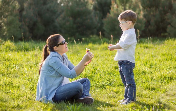 Son giving bouquet of flowers to mother in field