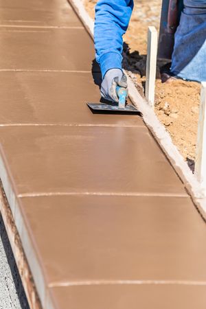 Construction Worker Using Stainless Steel Edger On Wet Cement Forming Coping Around New Pool