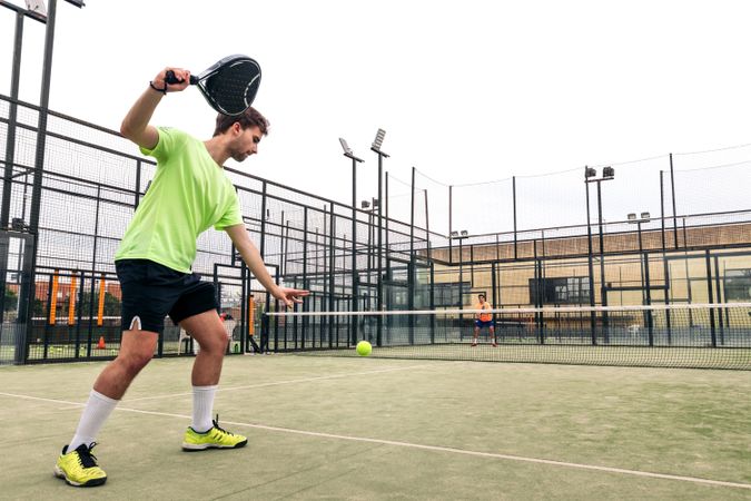 Young man serving in a paddle tennis game