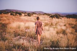Woman in short dress standing on brown grass field 43BjP5