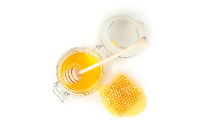 Glass jar, honeycomb and dipper isolated on neutral background