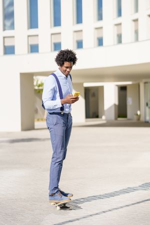 Man on skateboard checking his yellow smart phone