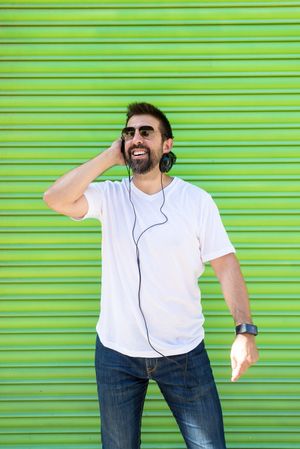 Smiling man in headphones and glasses in front of green background