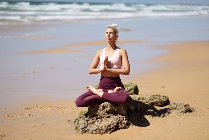 Peaceful woman sitting on a rock on a Spanish beach