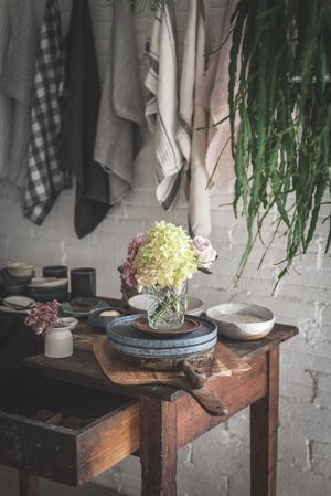 Table with flowers in vase on trays near towels hanging on thread
