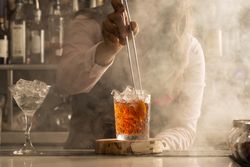 Cropped image of bartender adding orange slice to a cocktail