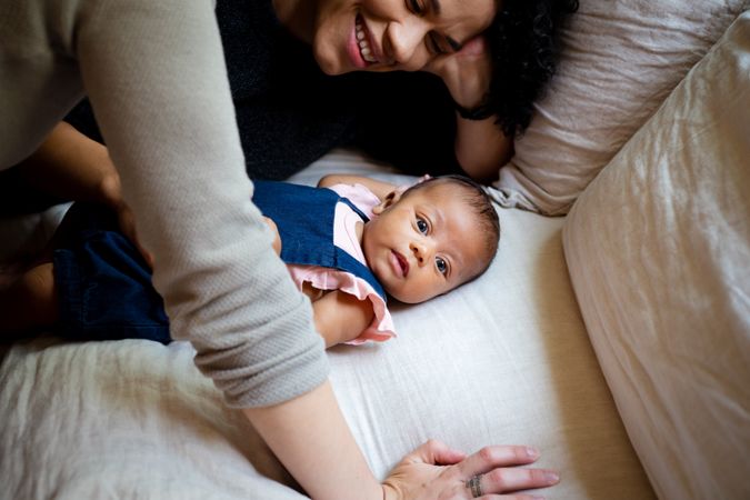 Baby laying on back surrounded by her parents