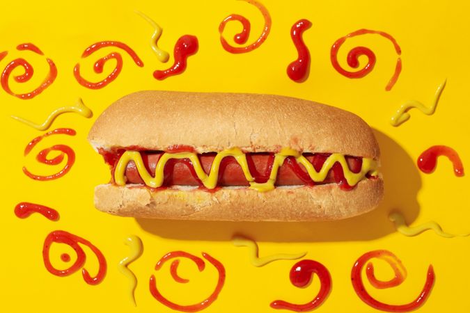 Tasty hot dog and sauces on yellow background