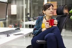 Smiling businesswoman with mug resting in office