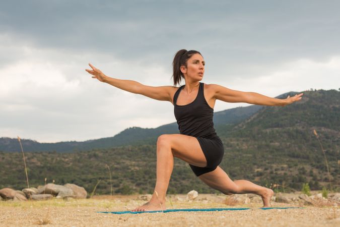 Woman practicing yoga outdoors near water