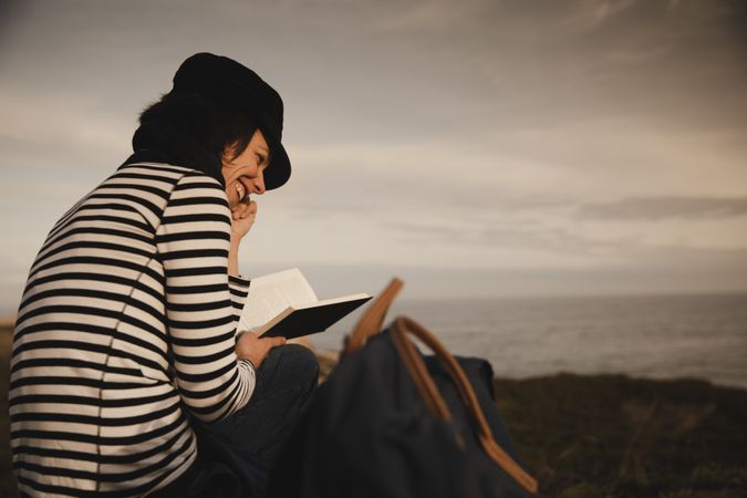 Woman with book on grass near lighthouse